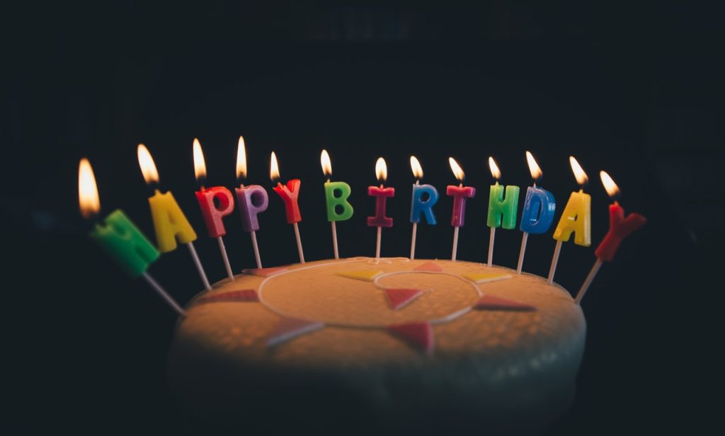 Birthday cake with lighted candles saying Happy Birthday in the dark