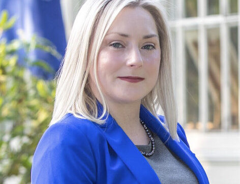 Anna Payne wearing a blue dress jacket and standing