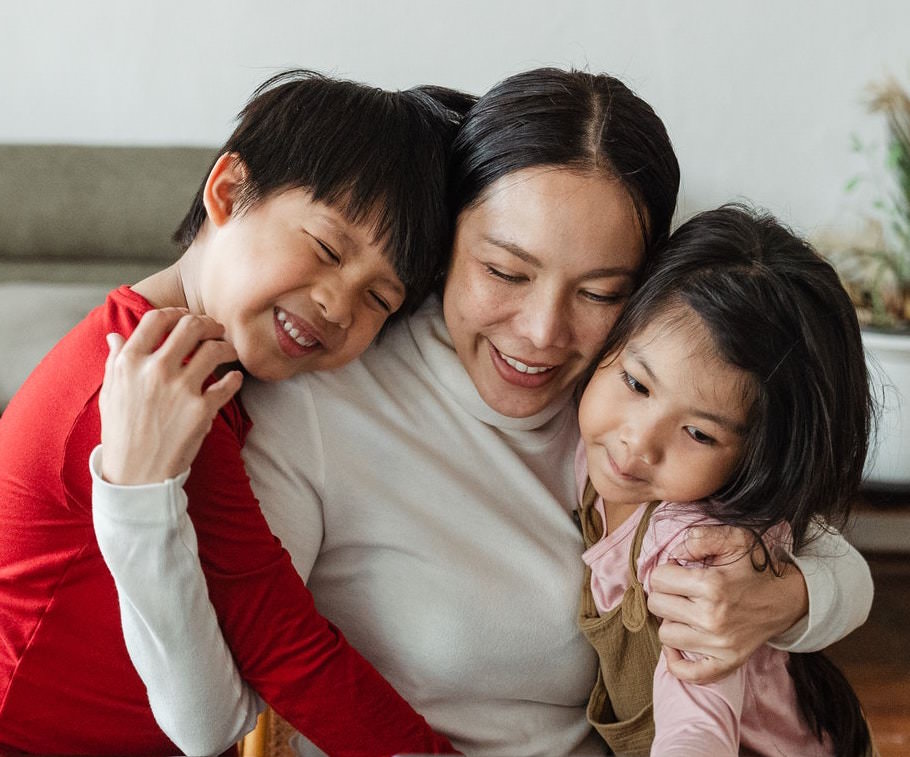 Woman hugging two children smiling